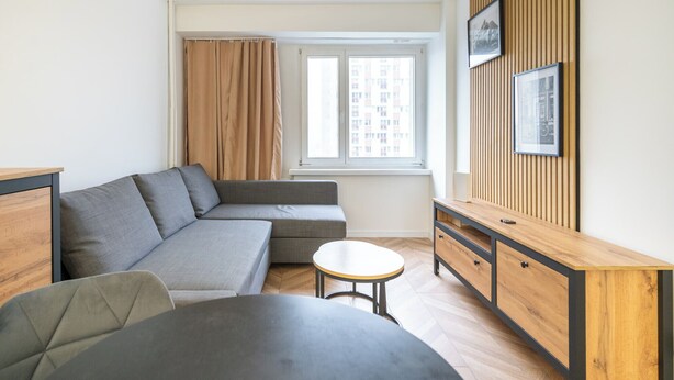A modern living room with a grey sofa, a small round table, and a wooden cabinet with drawers.