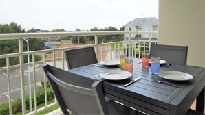 Un balcón con mesa lista para dos, sillas y vistas a una zona residencial.