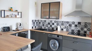 Una cocina compacta con lavadora, cafetera y comedor con mesa y sillas.