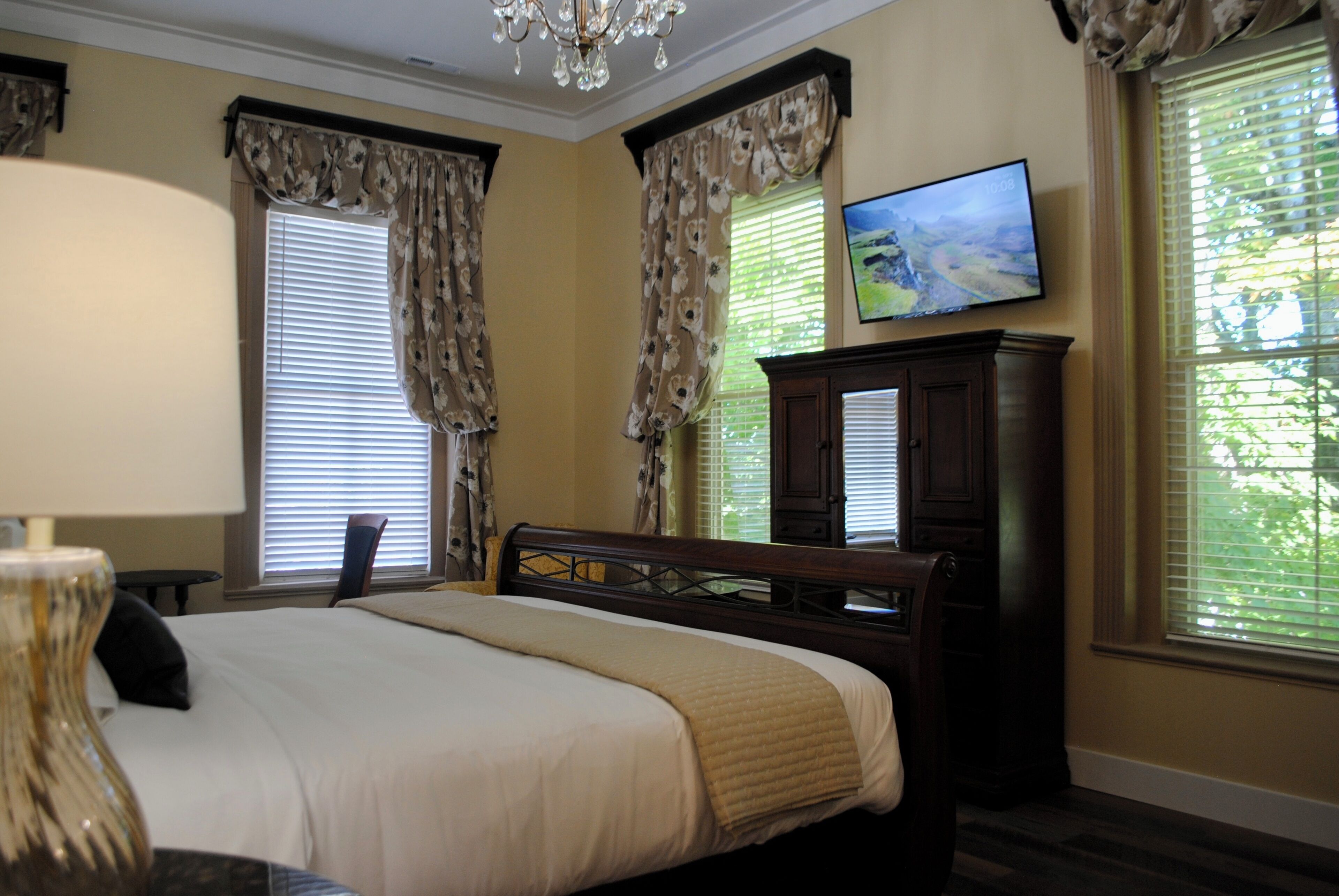 A hotel room with a bed, a television mounted on the wall, and a window with curtains.