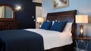 Ein ordentlich bezogenes Bett mit blau-weißer Bettwäsche, einem hölzernen Kopfteil und zwei Nachttischlampen.