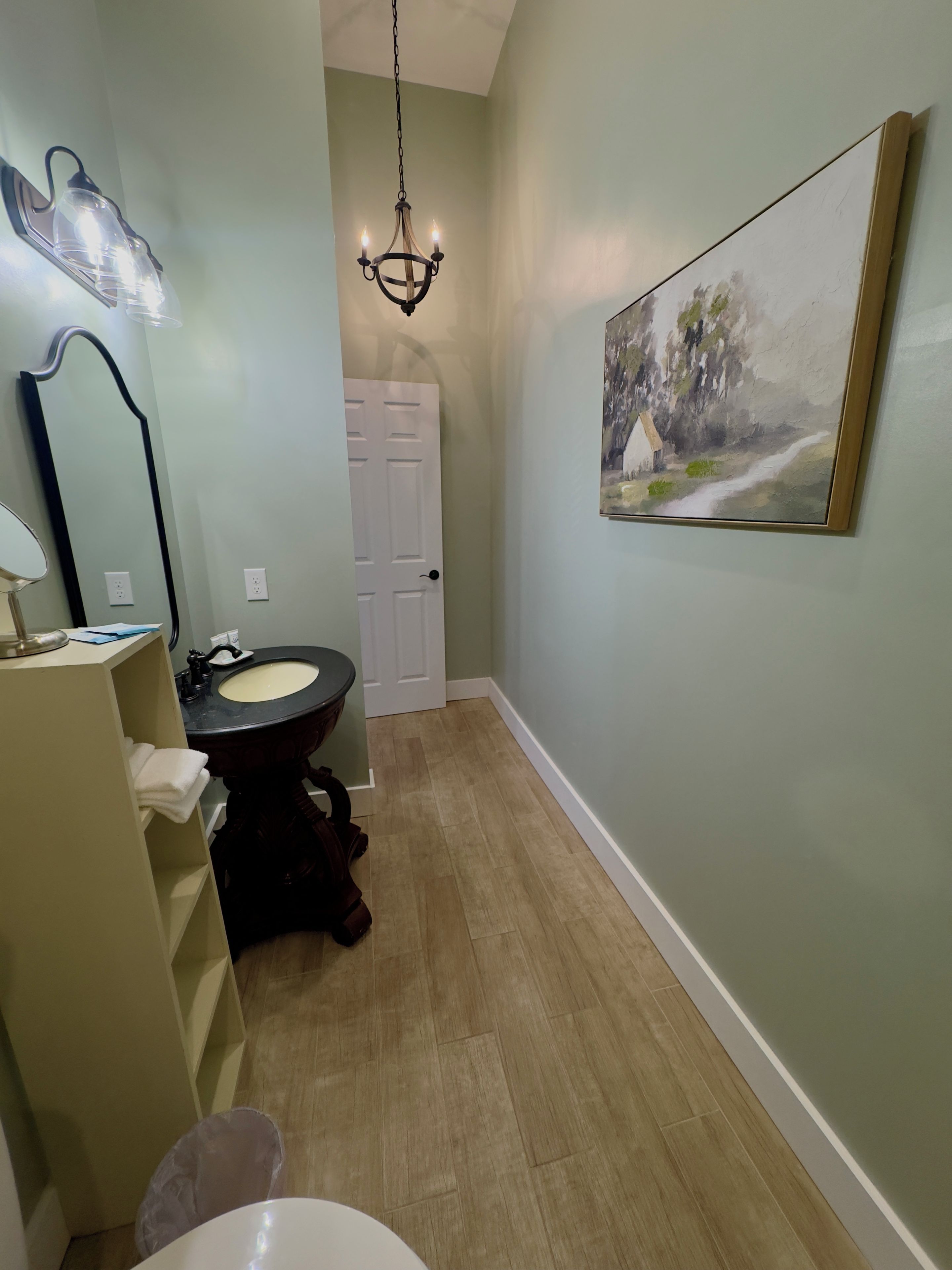 A bathroom with a vanity, sink, mirror, and a chandelier.