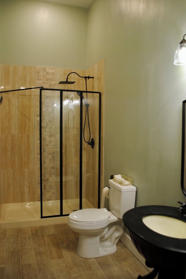 A bathroom with a shower enclosure, toilet, and sink. - The Lodge at Old City Hall (Jefferson City)