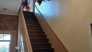 Eine prächtige Treppe mit einer Chandelüster, einer Ziegelwand und Blick ins Freie.