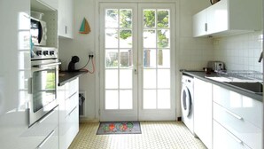 A kitchen with white cabinets, a built-in oven, a microwave, a washing machine, and a sink. - Frégate Saint Hilaire de Riez (SAINT HILAIRE DE RIEZ)