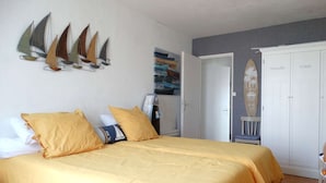 A bedroom with a bed, yellow bedding, and sailboat decorations on the wall. - Frégate Saint Hilaire de Riez (SAINT HILAIRE DE RIEZ)
