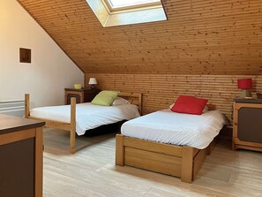 A bedroom with two wooden beds, a desk, and a skylight.
