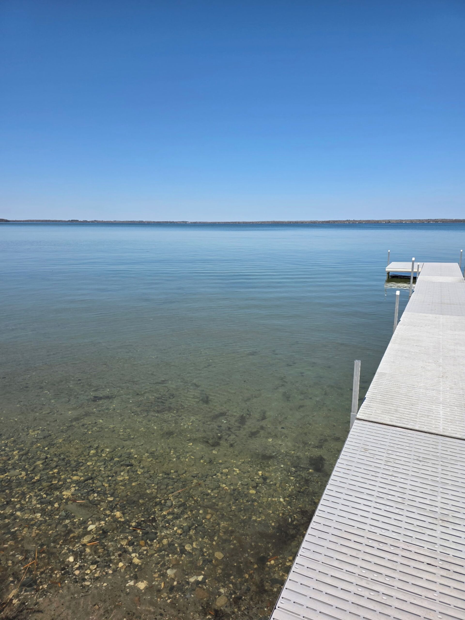 A clear view of a calm lake with a wooden dock extending into the water.