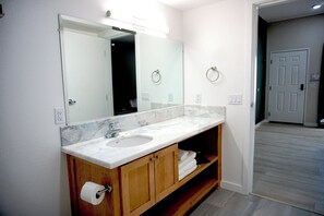 A bathroom with a marble sink, wooden vanity, and a large mirror.