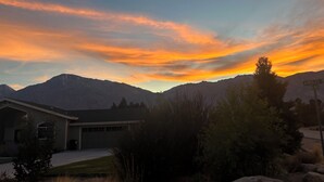 Ein Haus mit Garage, umgeben von Bergen und einem Abendhimmel.