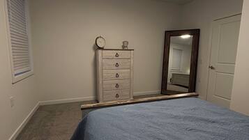 Un dormitorio con cama, cómoda y espejo.