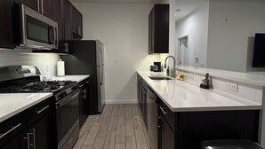 A modern kitchen with dark cabinets, stainless steel appliances, and a white countertop. - Welcome to outlet Charming townhome with WiFi and AC & more in enjoyable Bayonne (Bayonne)
