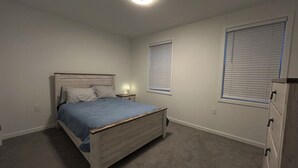 A bedroom with a single bed, a nightstand, a dresser, and a window with blinds. - Welcome to outlet Charming townhome with WiFi and AC & more in enjoyable Bayonne (Bayonne)