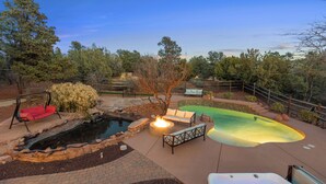 A backyard with a hot tub, a small pond, and a fire pit. - Experience luxury at the Sedona House of Wren & Koi, a spacious 5-bedroom retreat! (Sedona)