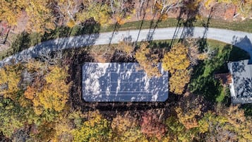 An aerial view of a solar panel installation surrounded by autumn foliage.