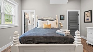 A bedroom with a bed, a dresser, a nightstand, and a window with blinds.