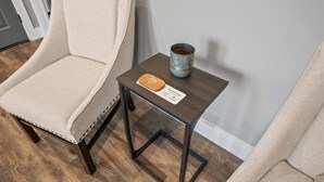 Ein beiger Sessel, ein kleiner Holztisch mit Untersetzer und einer Willkommenskarte, sowie eine Keramiktasse auf dem Tisch.