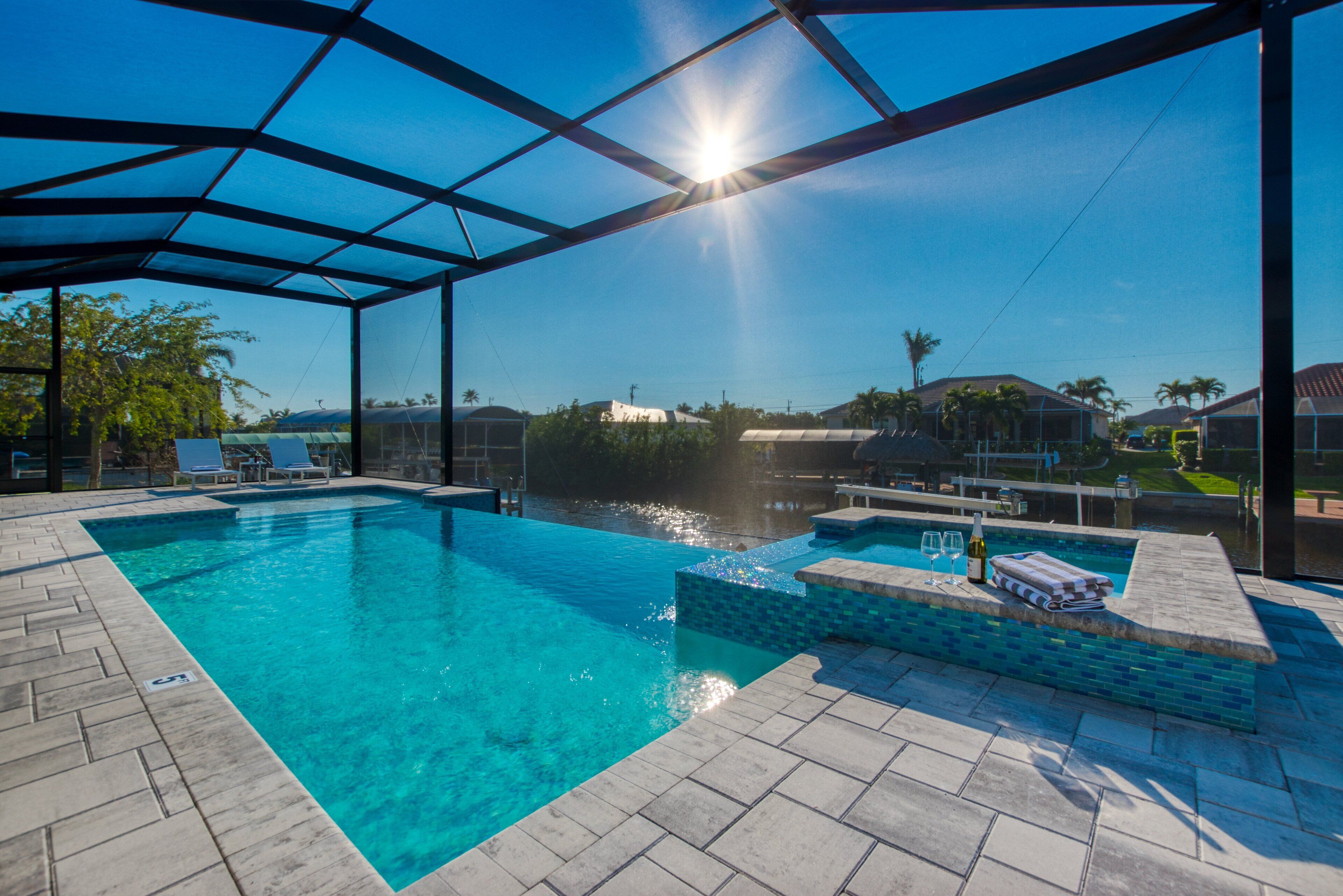 Une piscine dotée d’un parasol, de chaises longues et d’une petite cascade décorative.
