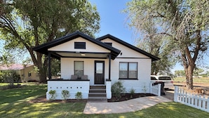 A two-story house with a front porch, a small deck, and a white picket fence. - Cozy Ranch House (Fredonia)