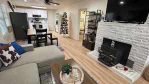 A modern living room with a fireplace, a television, and a dining area. - Cozy Ranch House (Fredonia)