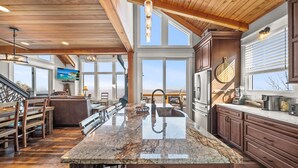 Una cocina amplia con una isla grande, techo de madera y ventanas que ofrecen vistas al exterior.