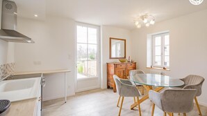 Una cocina moderna con una mesa de comedor de vidrio, sillas grises, un mueble de madera y un ventanal grande.