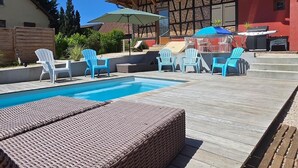 Piscina con sillones de descanso y zona de barbacoa.