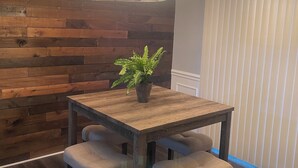 A dining area with a wooden table and four chairs, a hanging light fixture, and a potted plant. - Charming 2bedroom house with WiFi, AC in peaceful Indianapolis. Quiet cul-de-sac (Indianapolis)