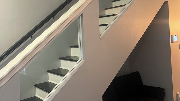 A staircase with glass railings and a dark-colored couch in the adjacent room. - Charming 2bedroom house with WiFi, AC in peaceful Indianapolis. Quiet cul-de-sac (Indianapolis)