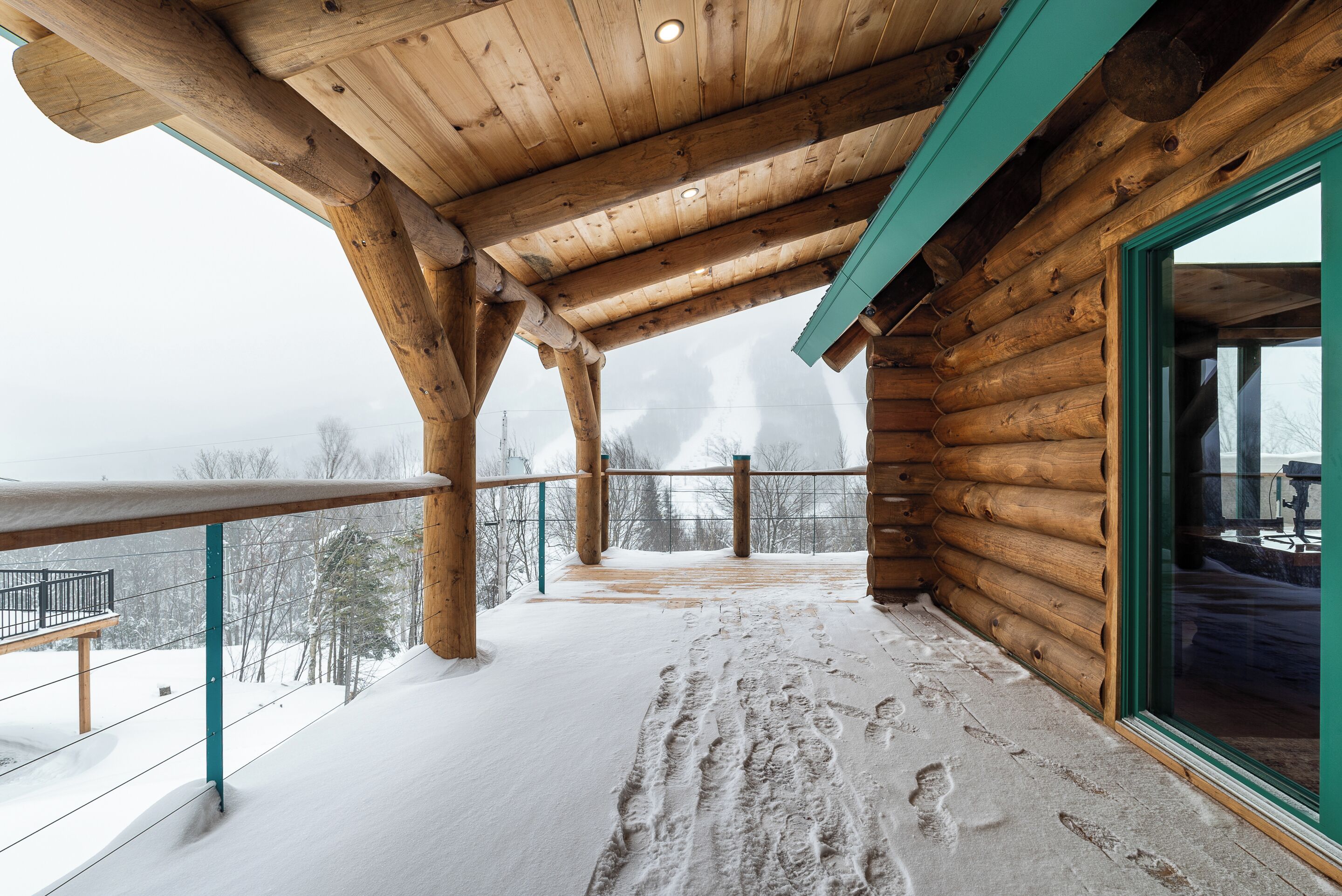 Une cabane en bois dotée d’un balcon et d’une porte en verre.