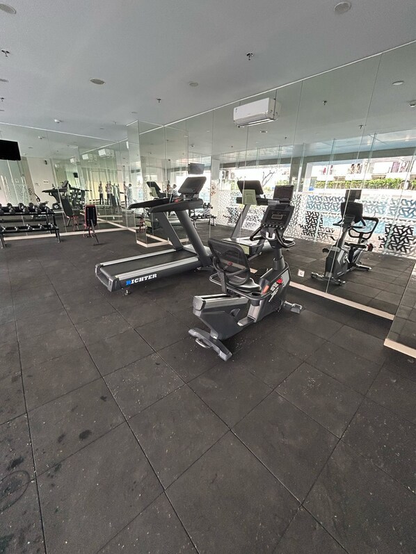 Una palestra con tapis roulant, cyclette e macchinari per pesi.
