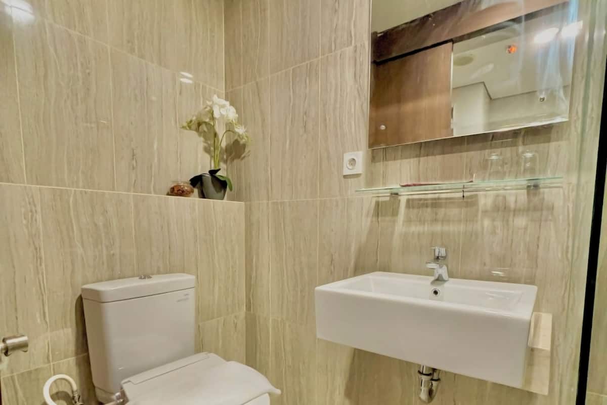 A modern bathroom with a toilet, sink, and a mirror above the sink.