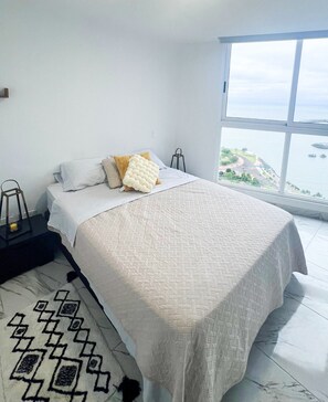 Une chambre dotée d’un grand lit, offrant une vue sur la mer et présentant un design moderne.