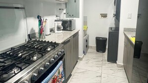 Moderni keittiö, jossa on kaasuliesi, mikroaaltouuni ja ruostumattomasta teräksestä valmistetut kaapit.