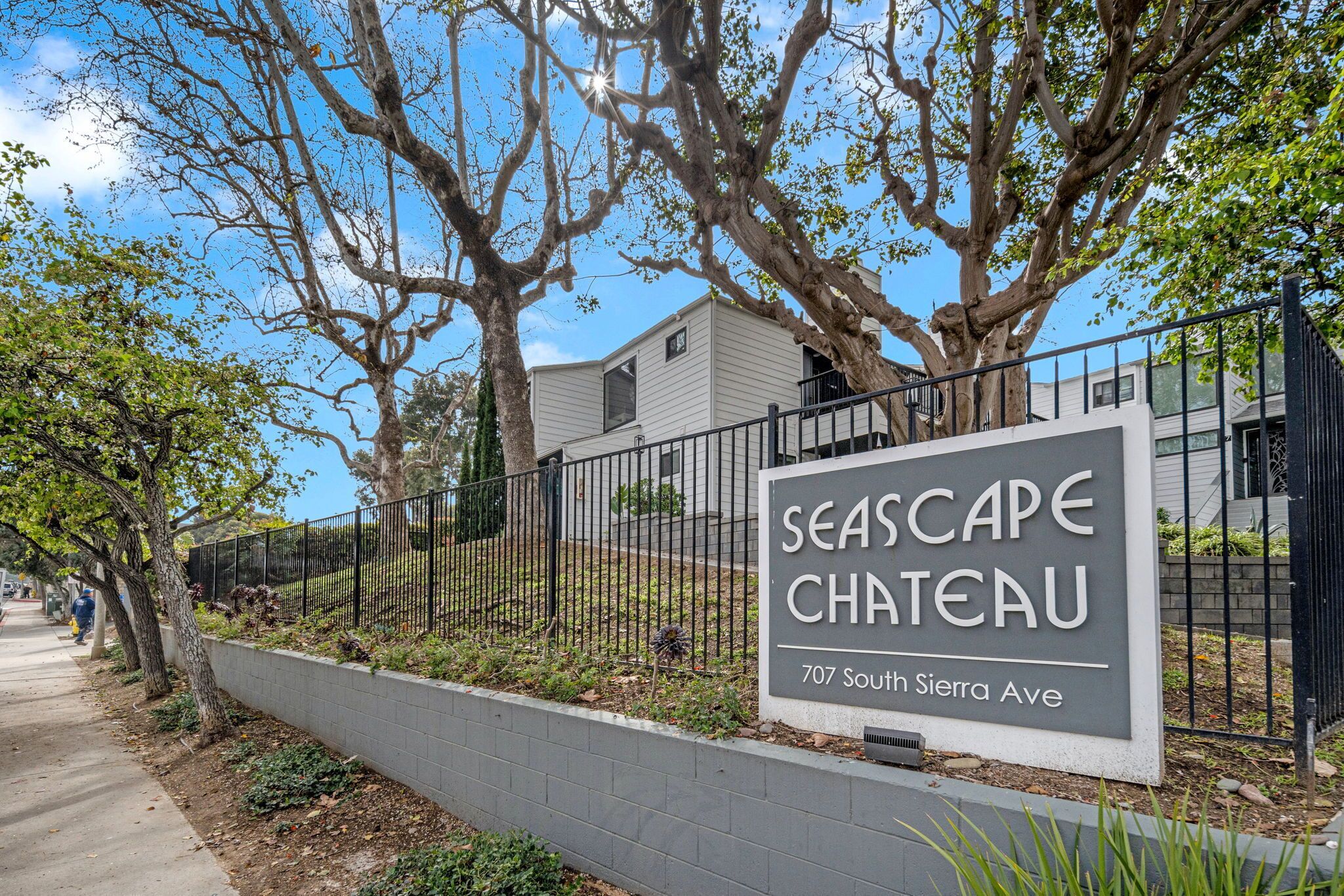 A gated property named Seascape Chateau at 707 South Sierra Ave, featuring a paved walkway and mature trees.