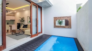 Un espace de vie moderne doté d’une piscine, d’un coin repas et d’une cuisine, le tout visible à travers une porte coulissante ouverte.