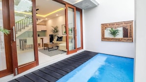 Un intérieur moderne avec une porte vitrée donnant sur un espace de vie, une petite piscine et un tableau encadré au mur.
