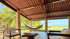 Un área de estar al aire libre con techo, una hamaca, muebles de madera y vistas al paisaje.