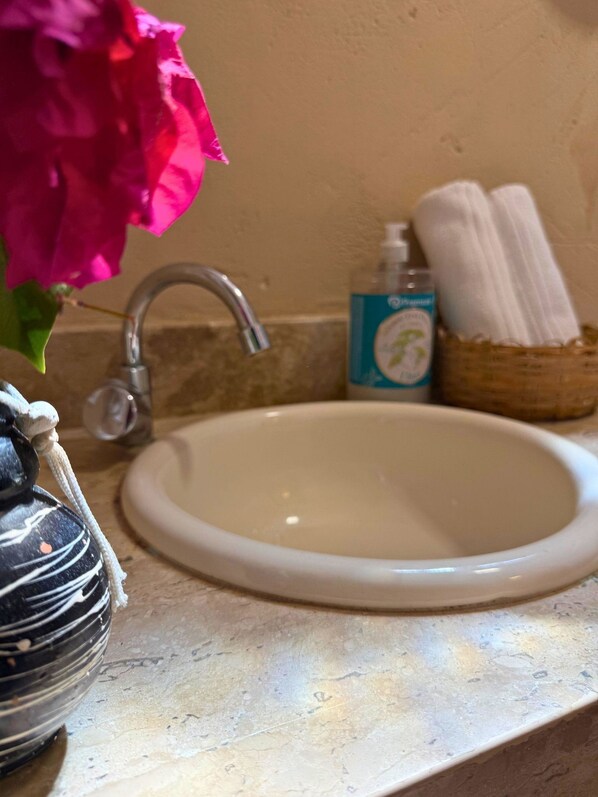 A bathroom sink with a faucet, a bottle of hand soap, and a basket with towels. - MHV Milagres- Casa Mar (São Miguel dos Milagres)