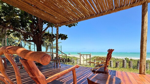 Una terraza de madera con vistas a la playa y al océano.