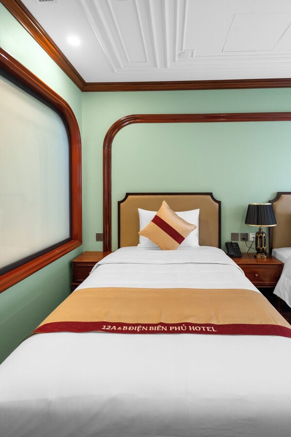 Une chambre d’hôtel avec un lit, une table de chevet, une lampe et une fenêtre.
