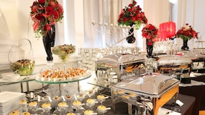 A buffet setup with various food items, including salads, appetizers, and desserts, arranged on glass tables.