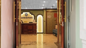 A hotel reception area with a reception desk, a waiting area, and a patterned wall.