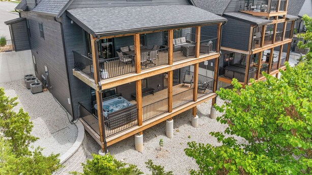 A multi-story building with a balcony on the ground floor, outdoor seating, and a view of the surrounding area.