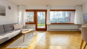 Ein modernes Wohnzimmer mit grauem Sofa, Couchtisch aus Holz und einem Fernseher auf einem Lowboard.