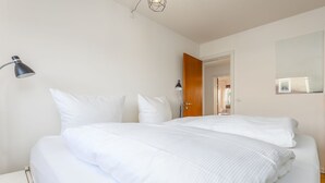 Ein Hotelzimmer mit einem großen Bett, zwei Nachttischlampen, einer Holztür und einem Spiegel an der Wand.