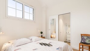 A bedroom with a bed, bedside table, lamp, and a chair.