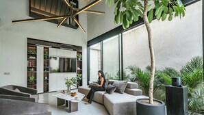A modern living room with a sofa, coffee table, and a large potted plant. - Villa Sabilla Bingin (Pecatu)