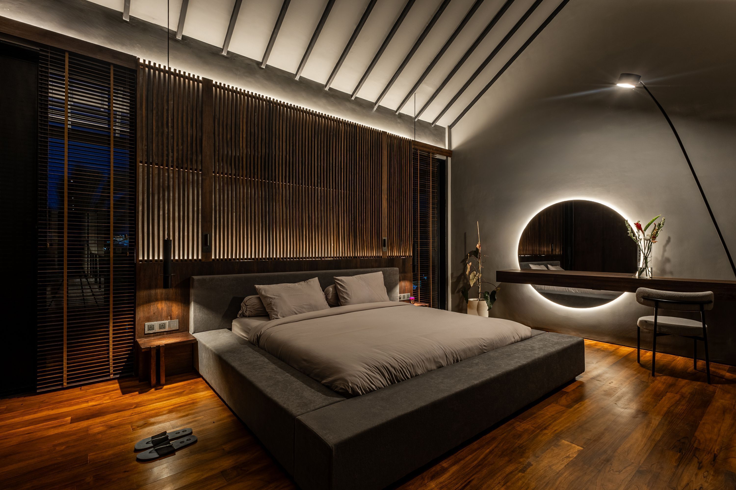 Une chambre moderne avec un grand lit, un plancher en bois et une table de chevet avec une lampe.