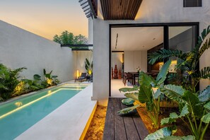 A modern house with a swimming pool, a wooden deck, and a dining area. - Villa Sabilla Bingin (Pecatu)